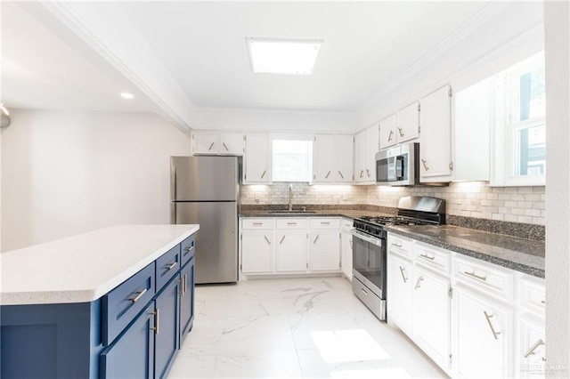 kitchen featuring appliances with stainless steel finishes, blue cabinets, sink, white cabinets, and a kitchen island