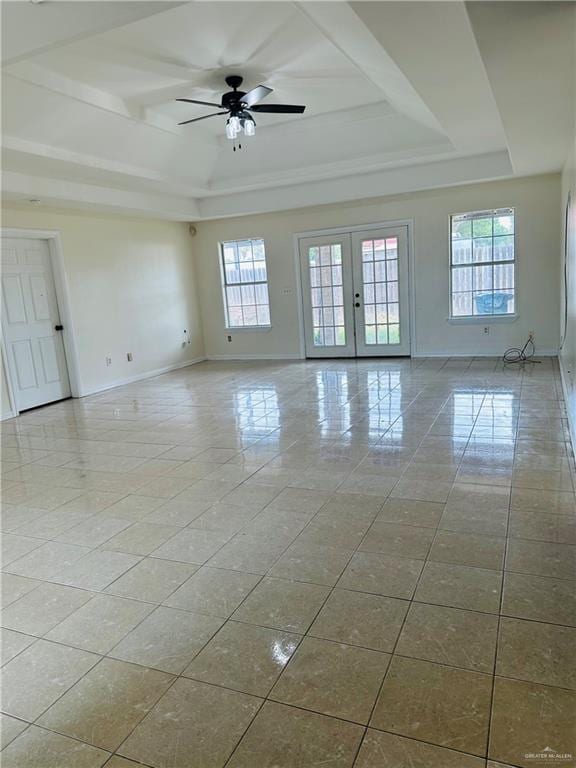 empty room featuring a tray ceiling, a wealth of natural light, french doors, and ceiling fan