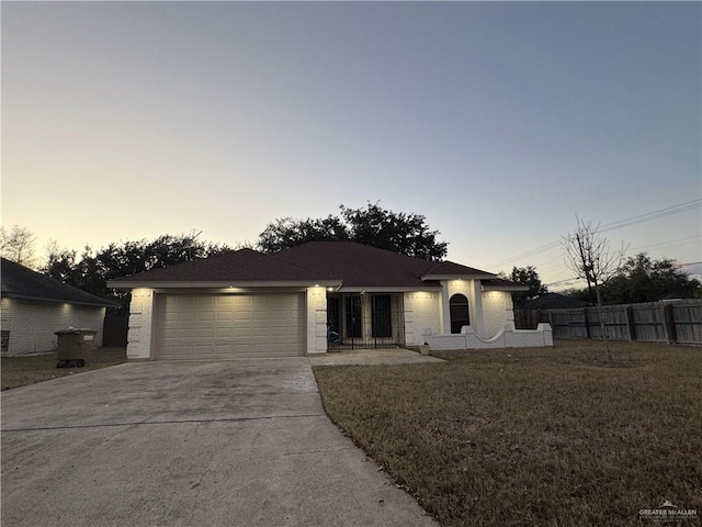 single story home with a garage and a lawn