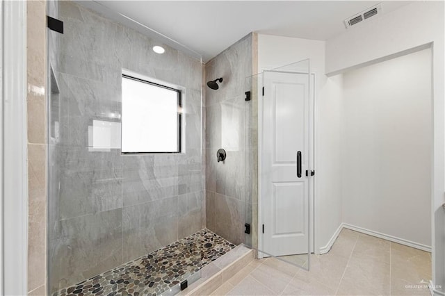 bathroom with a shower with shower door and tile patterned floors