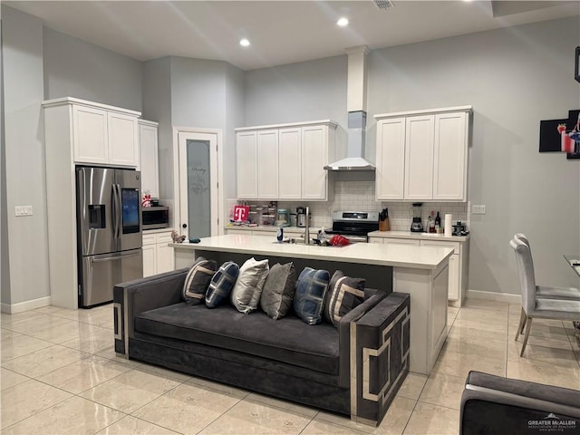 kitchen with white cabinetry, wall chimney exhaust hood, stainless steel appliances, and an island with sink