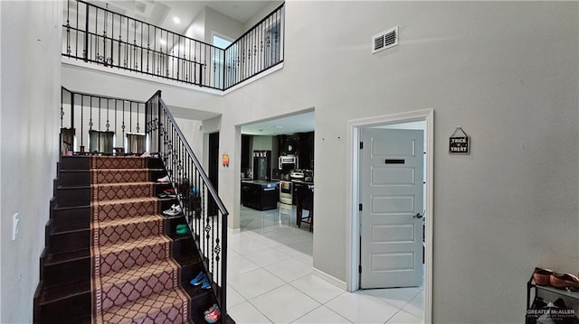 staircase featuring a high ceiling and tile patterned floors