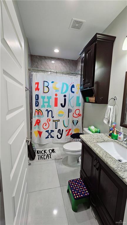 bathroom with tile patterned flooring, vanity, a shower with shower curtain, and toilet