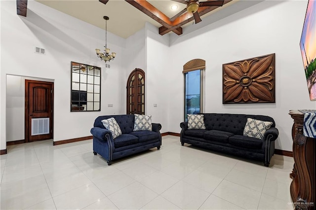 tiled living room with a towering ceiling and ceiling fan with notable chandelier