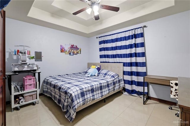 tiled bedroom featuring ceiling fan and a tray ceiling