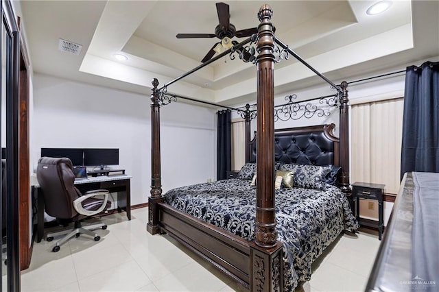 bedroom with ceiling fan, a tray ceiling, and light tile patterned floors