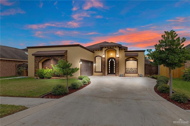 mediterranean / spanish home featuring a garage and a lawn