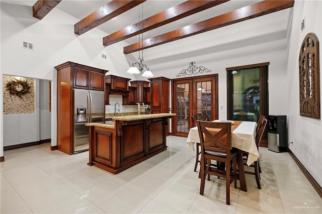 kitchen featuring pendant lighting, sink, stainless steel fridge, beam ceiling, and light stone counters