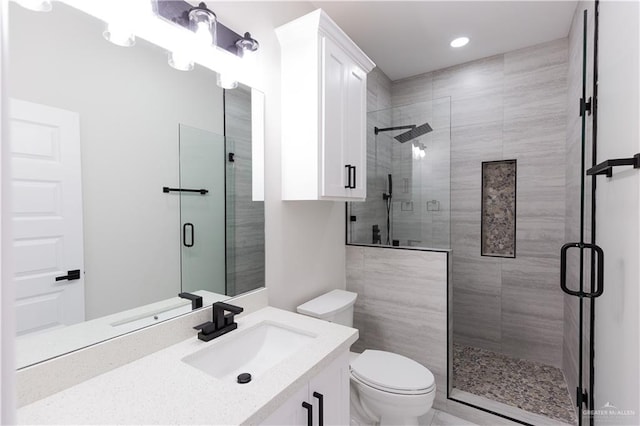 bathroom featuring vanity, toilet, and a shower with shower door