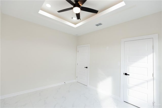 unfurnished room featuring ceiling fan and a raised ceiling