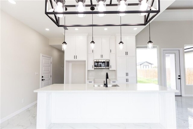 kitchen featuring pendant lighting, a spacious island, white cabinetry, and sink