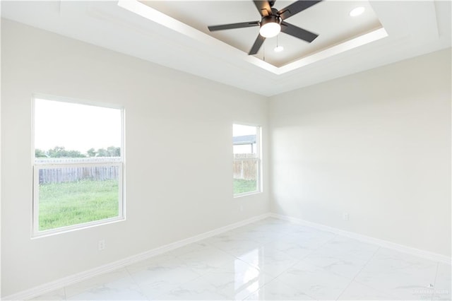 spare room with ceiling fan and a raised ceiling