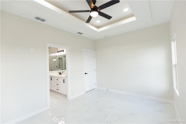 spare room with ceiling fan, a raised ceiling, and sink