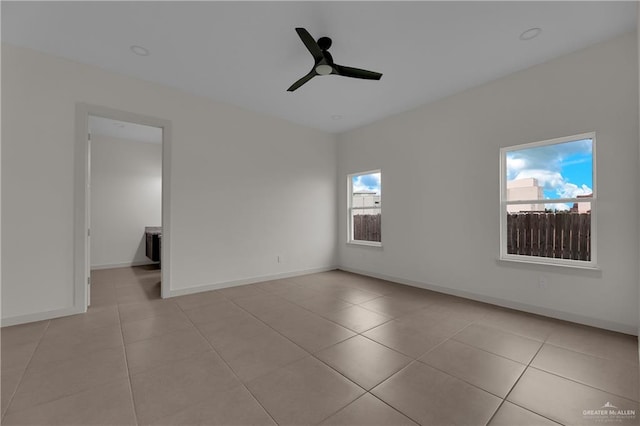 tiled empty room featuring ceiling fan and a healthy amount of sunlight