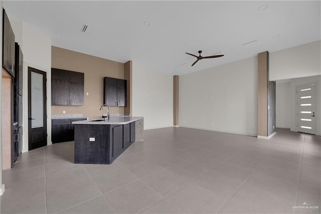 kitchen with ceiling fan, sink, light tile patterned floors, and a kitchen island with sink