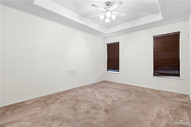 empty room with light carpet, ceiling fan, and a tray ceiling