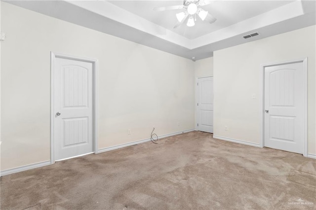 carpeted spare room featuring ceiling fan and a raised ceiling