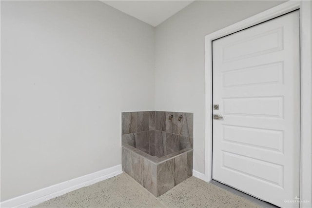 interior space featuring a bathing tub and baseboards