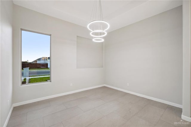 unfurnished room with baseboards and an inviting chandelier