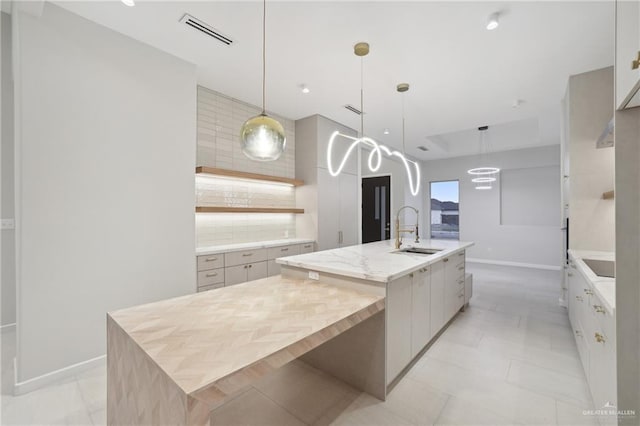 kitchen featuring a spacious island, a sink, visible vents, tasteful backsplash, and modern cabinets