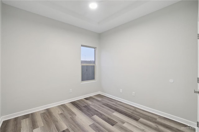 spare room featuring dark wood-type flooring and baseboards