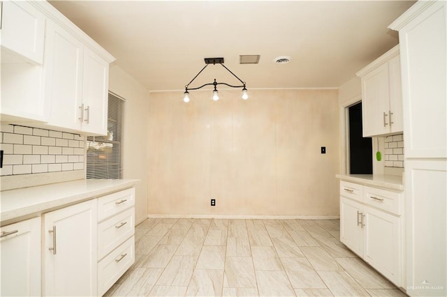 kitchen featuring white cabinets, backsplash, and hanging light fixtures