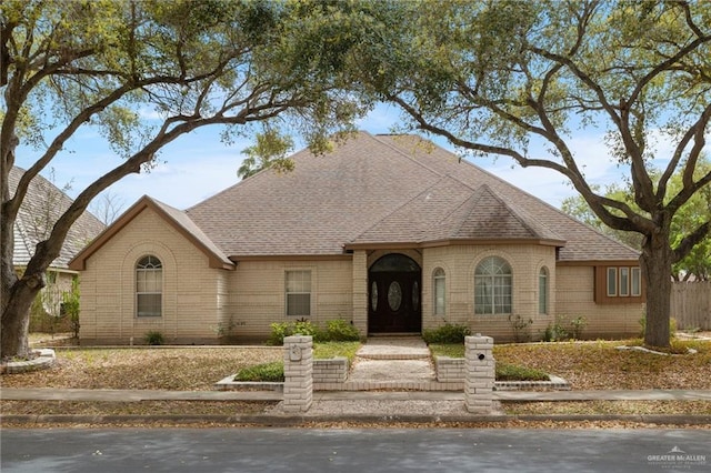 view of front of property with brick siding and roof with shingles