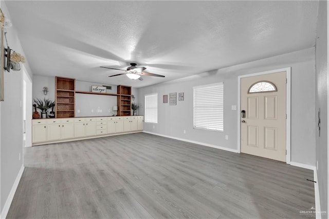 unfurnished living room featuring a textured ceiling, ceiling fan, and light wood-type flooring