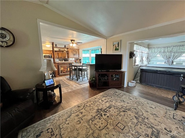 living room with ceiling fan, wood-type flooring, lofted ceiling, and crown molding