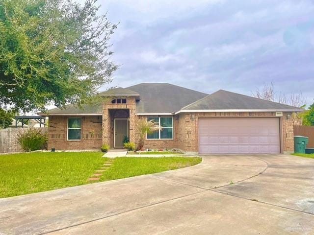 view of front of home with a front yard, concrete driveway, brick siding, and an attached garage