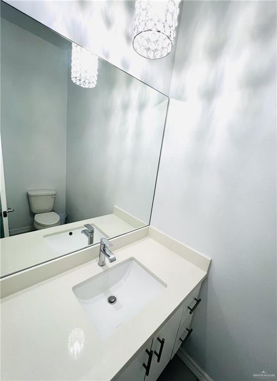 bathroom with vanity, an inviting chandelier, and toilet