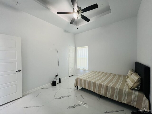 bedroom with a tray ceiling and ceiling fan