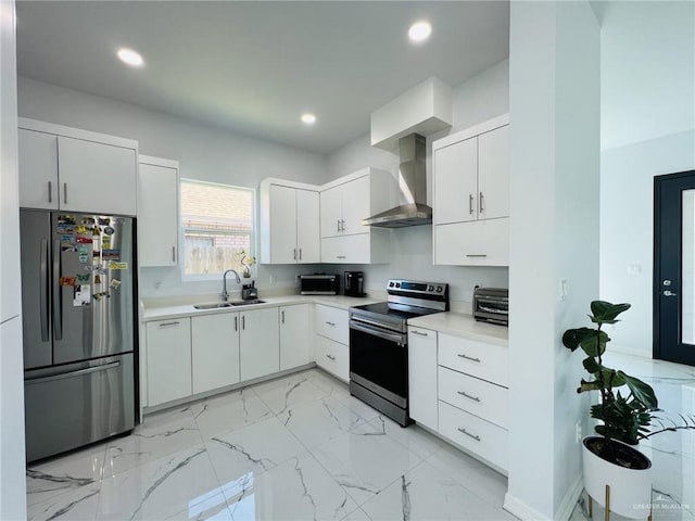 kitchen with appliances with stainless steel finishes, white cabinetry, wall chimney exhaust hood, and sink