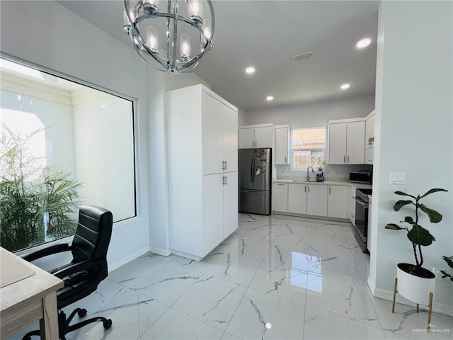 kitchen with sink, white cabinetry, stainless steel appliances, and an inviting chandelier