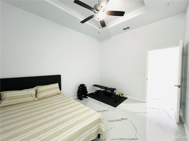 bedroom featuring a raised ceiling and ceiling fan