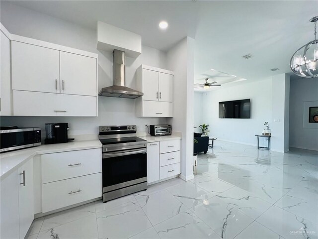 kitchen featuring white cabinetry, ceiling fan, wall chimney exhaust hood, hanging light fixtures, and stainless steel appliances