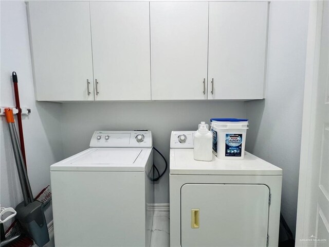 clothes washing area featuring cabinets and independent washer and dryer