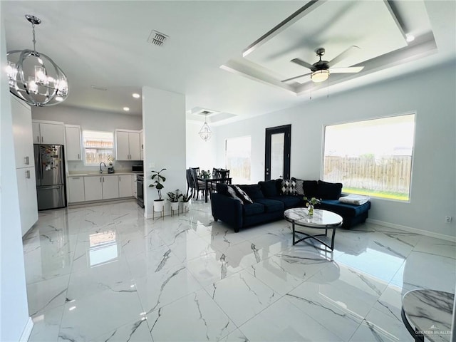 living room featuring ceiling fan with notable chandelier, a healthy amount of sunlight, and sink