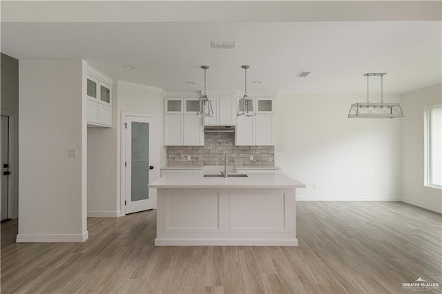 kitchen with white cabinetry, sink, hanging light fixtures, an island with sink, and decorative backsplash