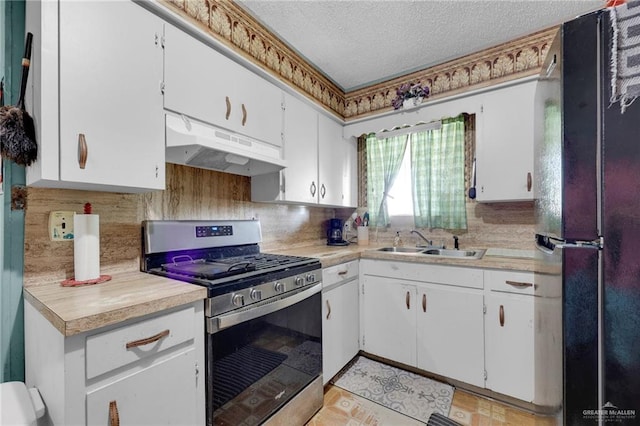 7027 Jo Din St, Edinburg, TX 78542 - kitchen featuring stainless steel gas range, under cabinet range hood, freestanding refrigerator, a sink, and light countertops