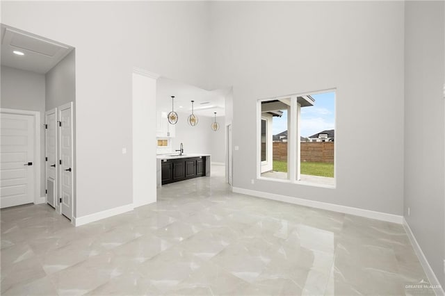 unfurnished living room featuring a high ceiling and sink