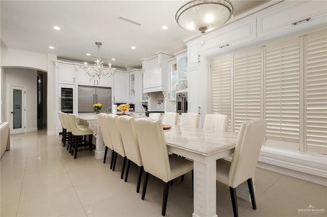 tiled dining space with wine cooler and a notable chandelier