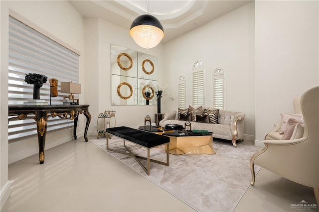 living room with concrete flooring, a high ceiling, and a tray ceiling