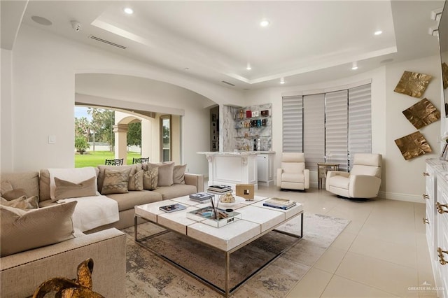 living room with a raised ceiling and light tile patterned floors