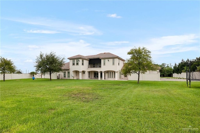 back of property with a balcony and a lawn