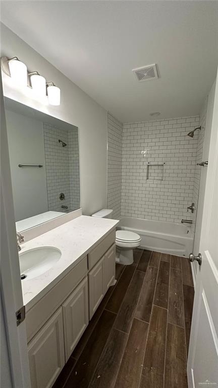 full bathroom featuring vanity, tiled shower / bath combo, and toilet