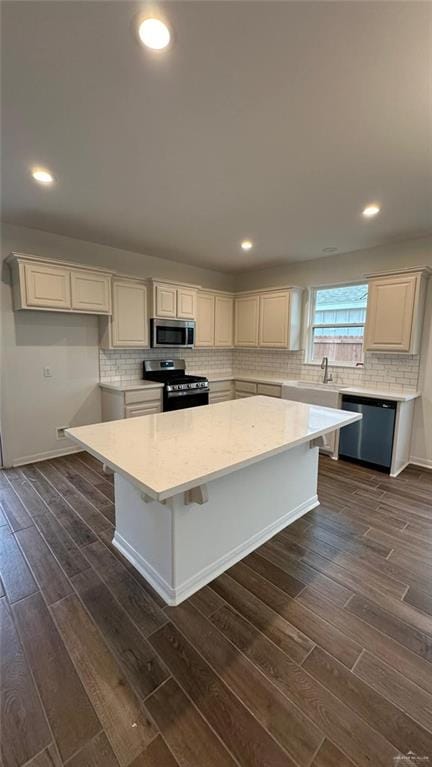 kitchen with white cabinets, appliances with stainless steel finishes, a kitchen island, and dark wood-type flooring