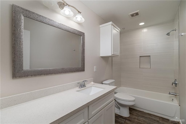 bathroom with visible vents, toilet, vanity, wood finished floors, and  shower combination