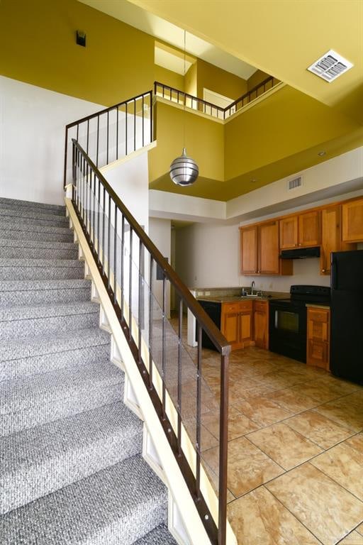 stairs with tile patterned flooring, a high ceiling, and sink