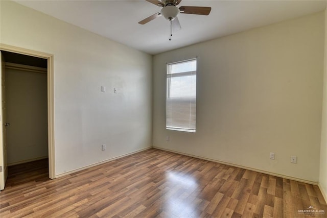 unfurnished bedroom with a walk in closet, ceiling fan, a closet, and light wood-type flooring